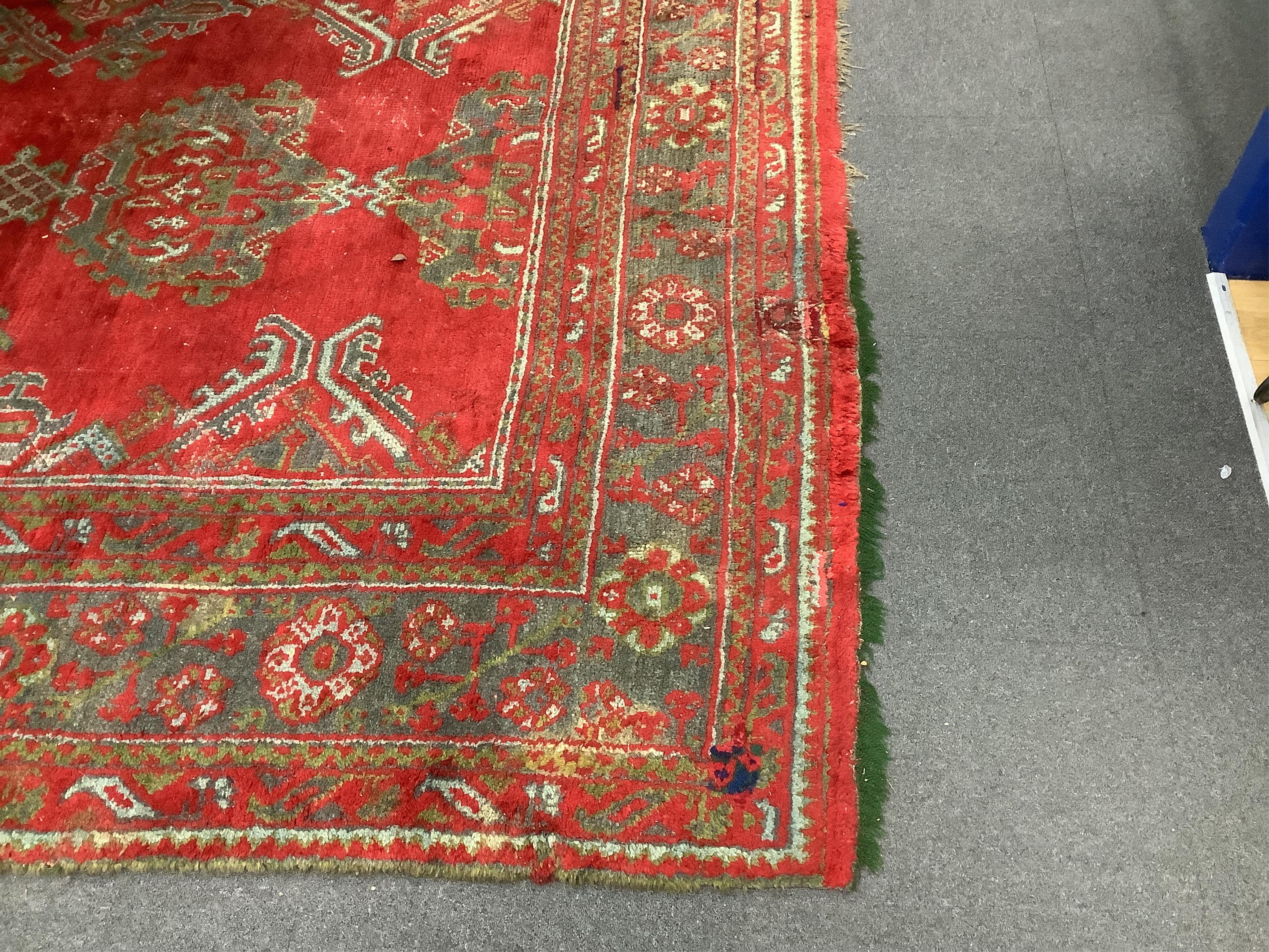 A large Turkish carpet, with triple row of stylised medallions on a red ground, multi bordered, 413 x 345cm. Condition